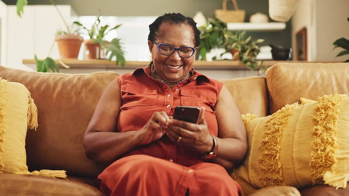 A woman smiles as she uses a phone. Community Calling helps people get access to phones for vital services and to stay in touch with loved ones.