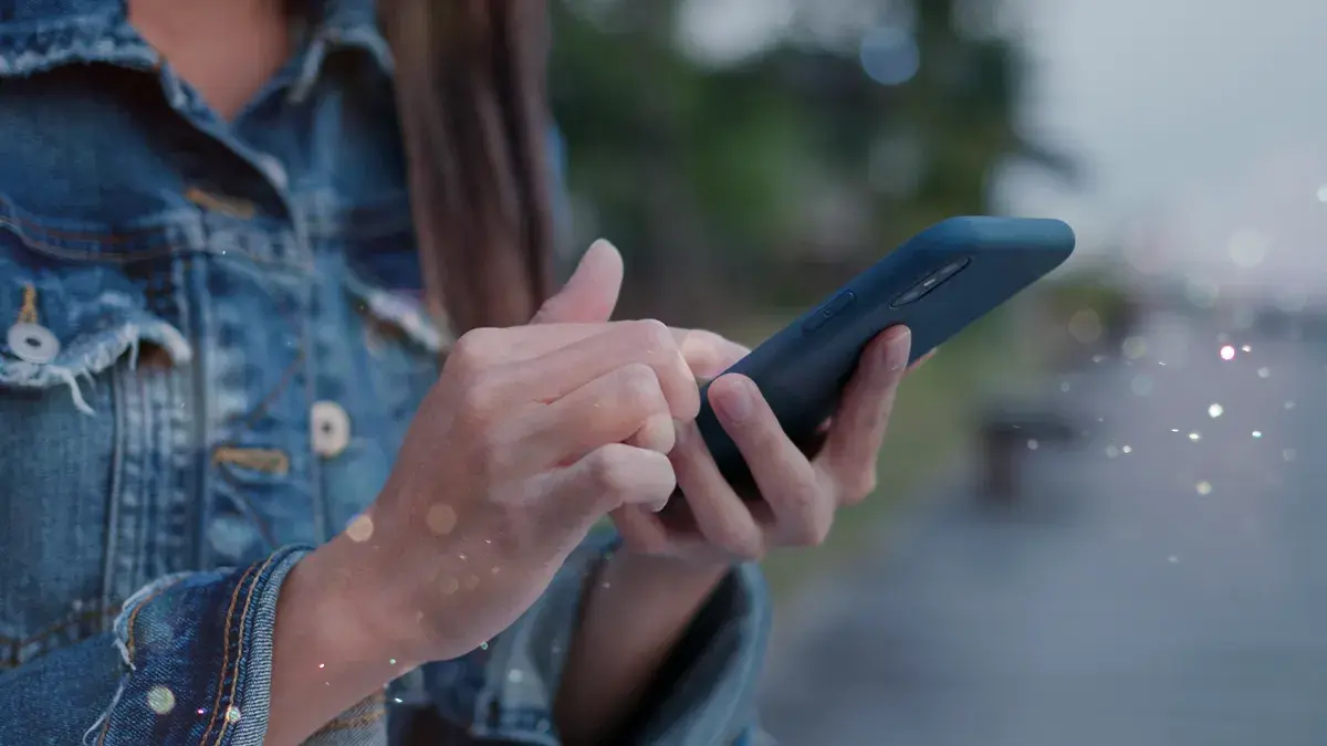 A person scrolls on their mobile phone. This is Virgin Media's guide to freeing up phone storage space.