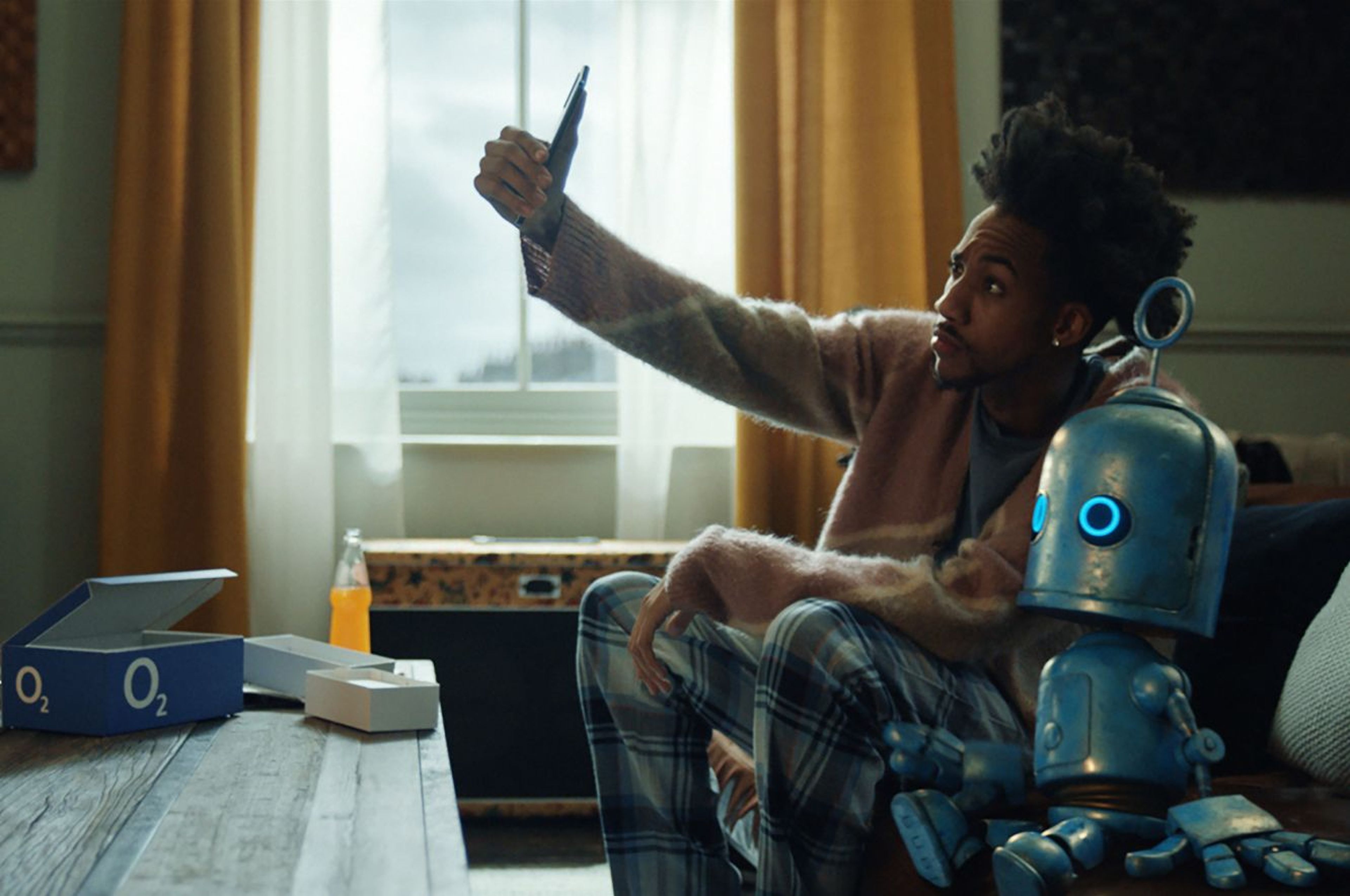 Man on couch sitting beside the bubble robot taking a selfie