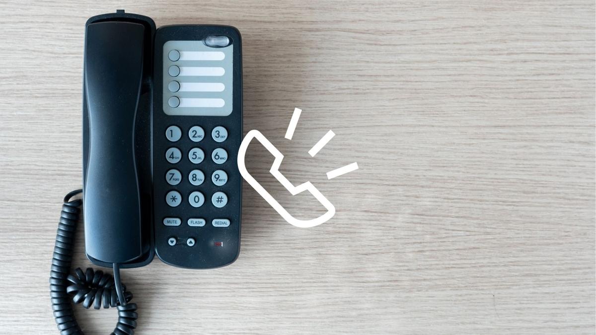 Black landline phone with cord on a wooden surface