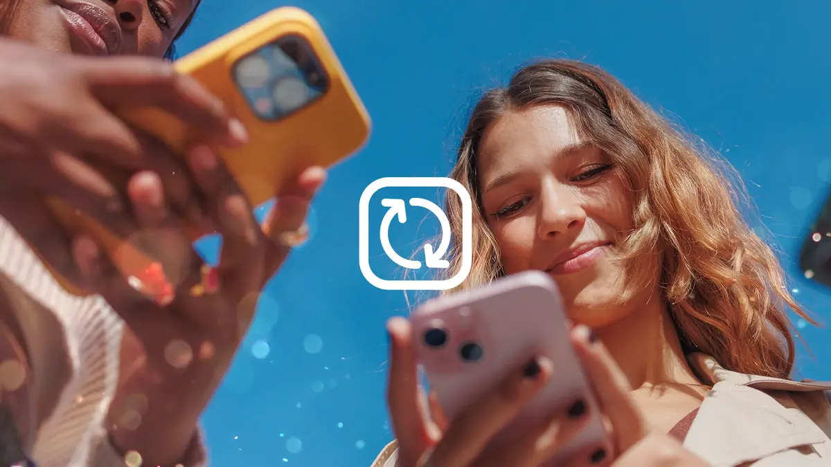 A young woman outdoors under blue skies looks at her mobile phone. This is Virgin Media's guide to freeing up phone storage space.