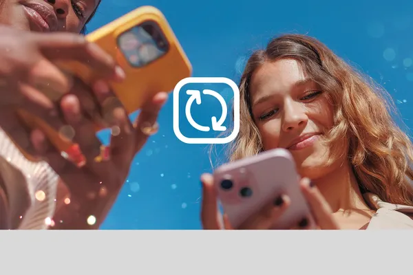 A young woman outdoors under blue skies looks at her mobile phone. This is Virgin Media's guide to freeing up phone storage space.