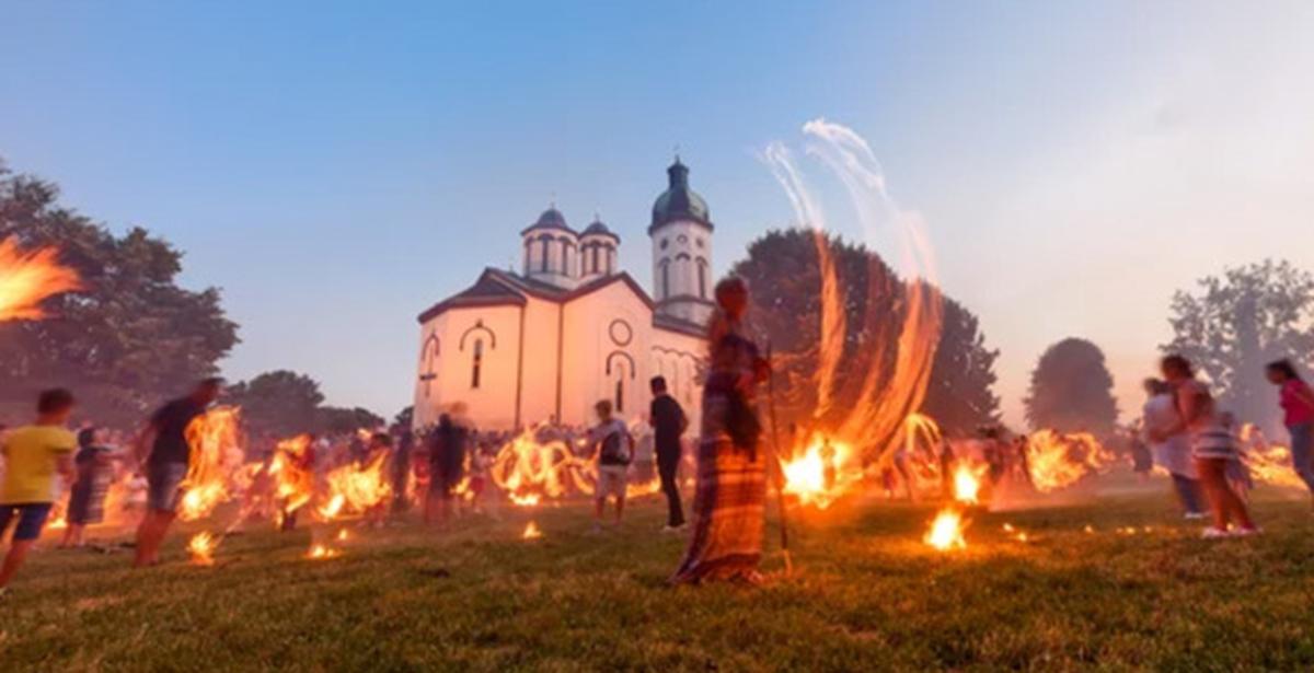 People dancing with fire with a white building in the background