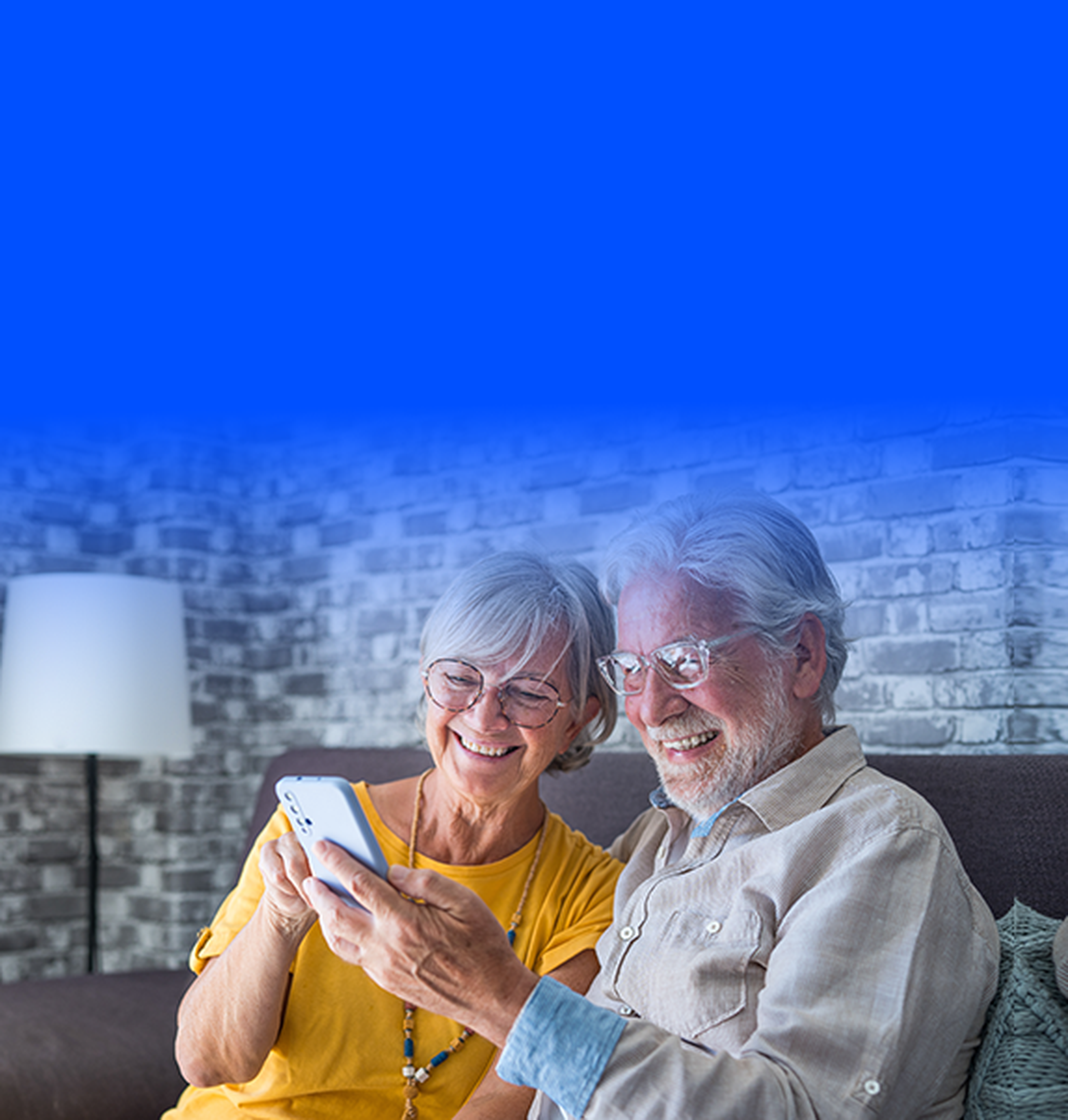 Older man and older woman smiling and looking at smartphone