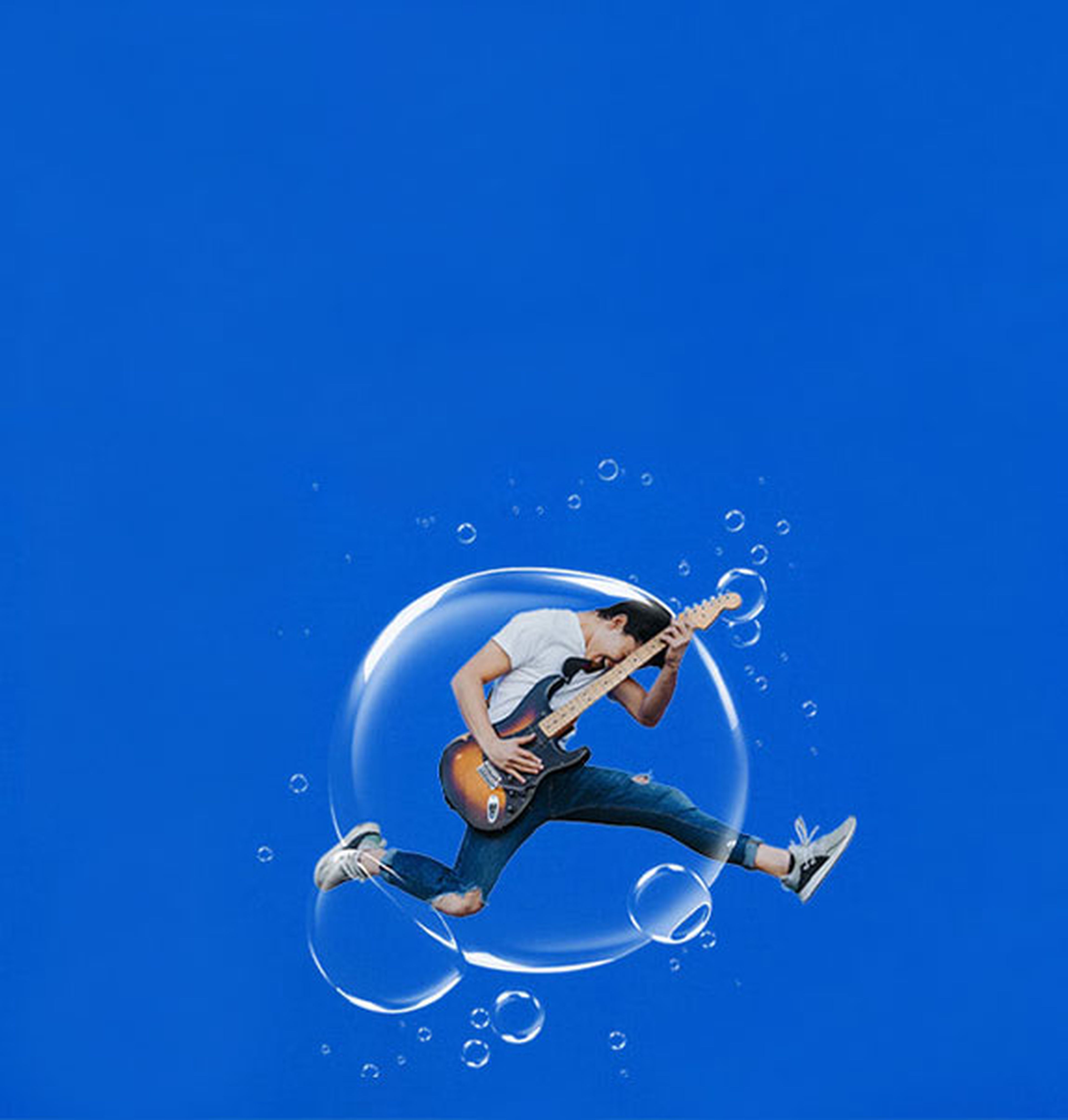 Man playing the guitar and jumping in a bubble