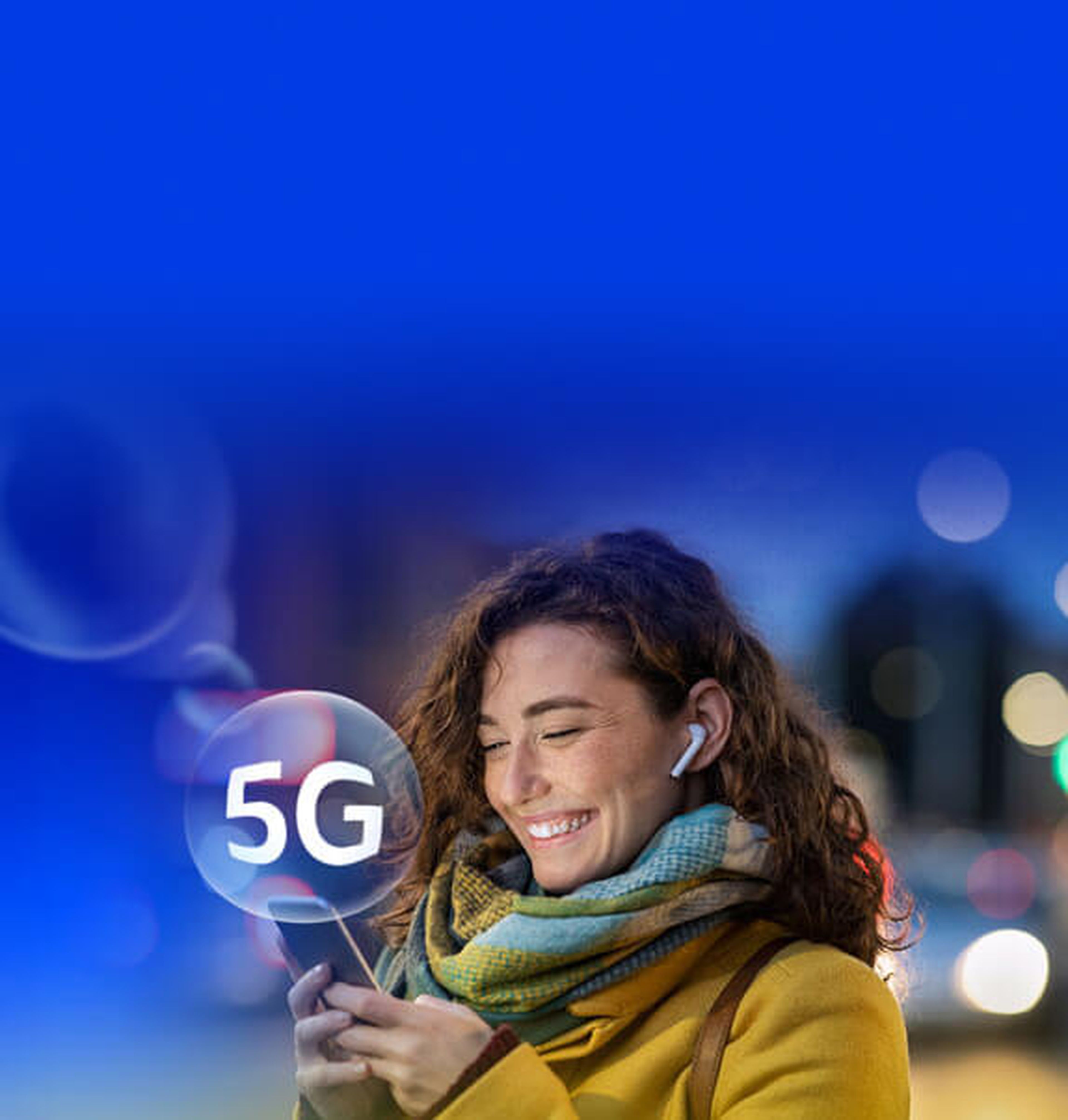 Woman wearing a yellow coat, a big scarf and an ear bud in one ear, looks at smartphone and smiles. Over the image there's a bubble with a 5G logo.
