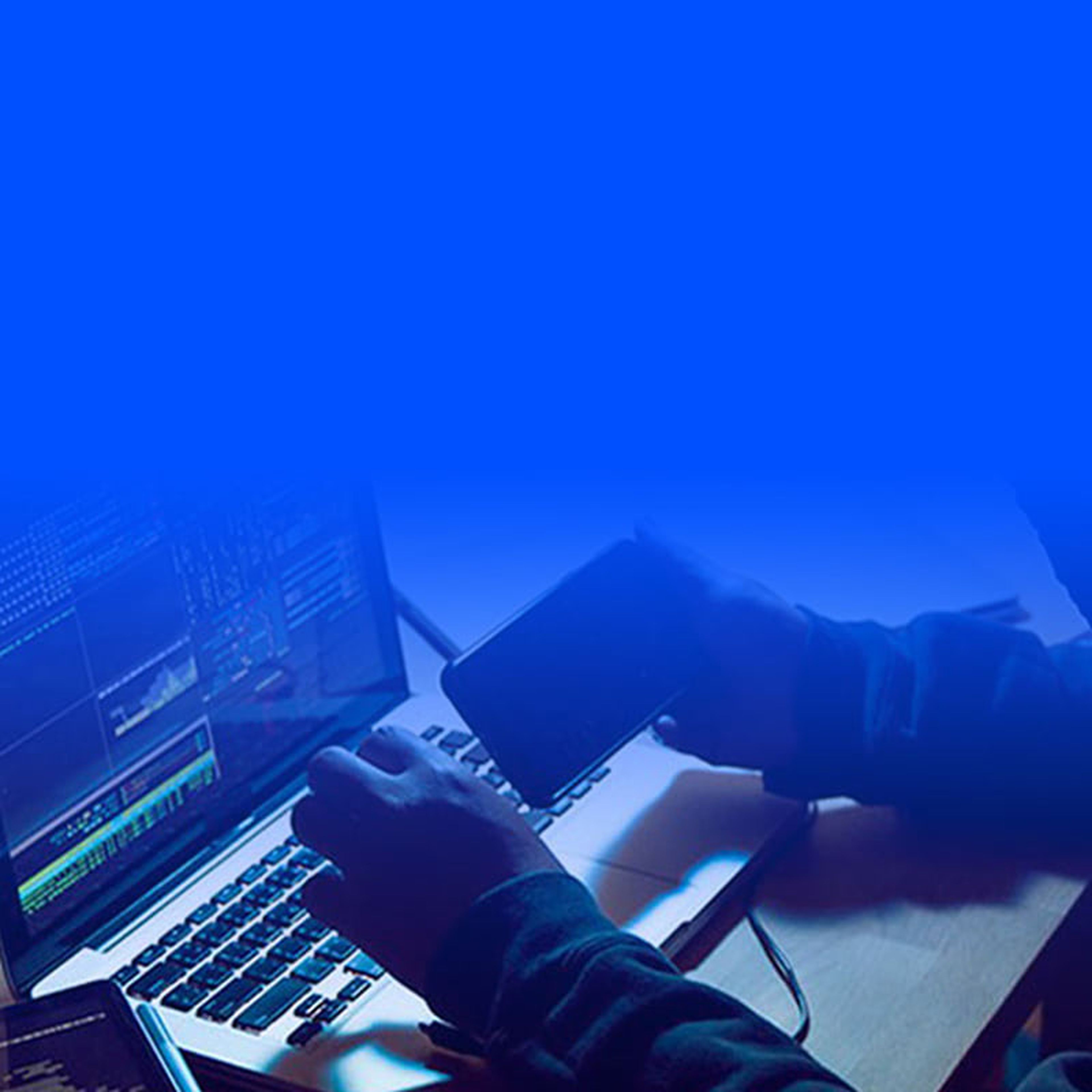 Person holding mobile phone with keyboard and PC screen