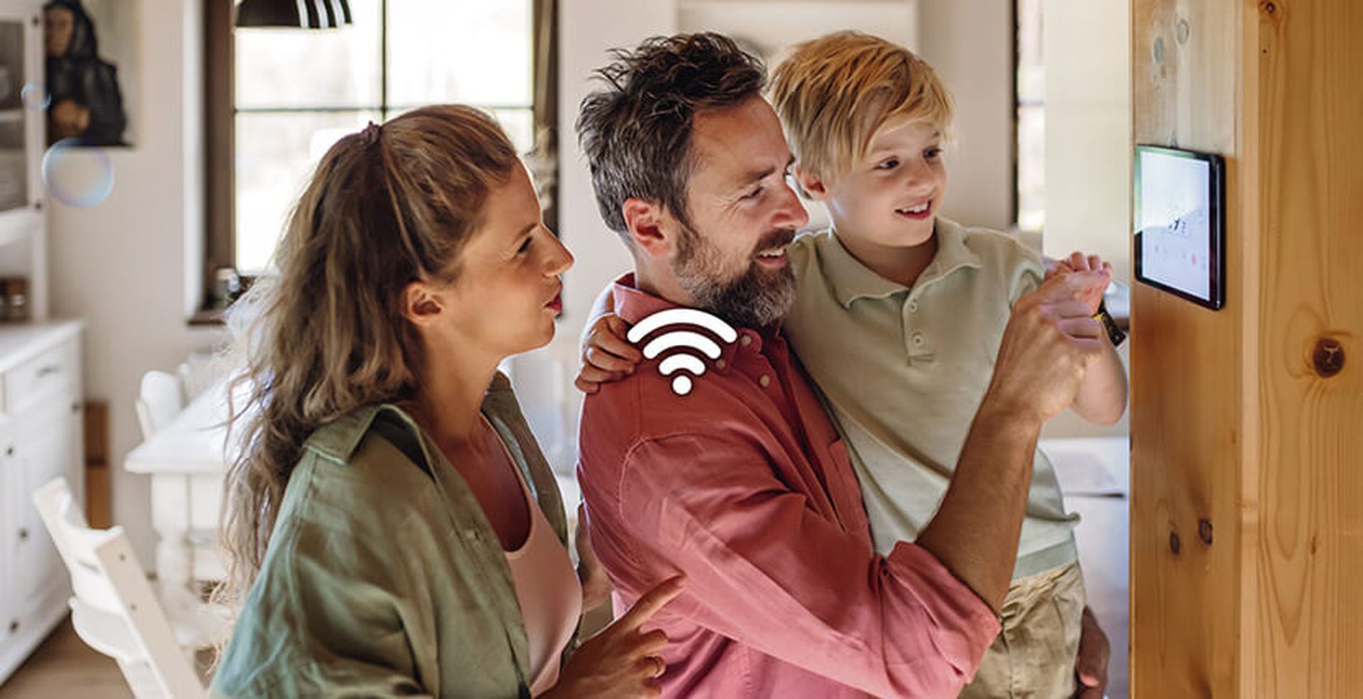 A family of three interacts with a smart home device on the wall, smiling and discussing. A Wi-Fi symbol is superimposed on the image.