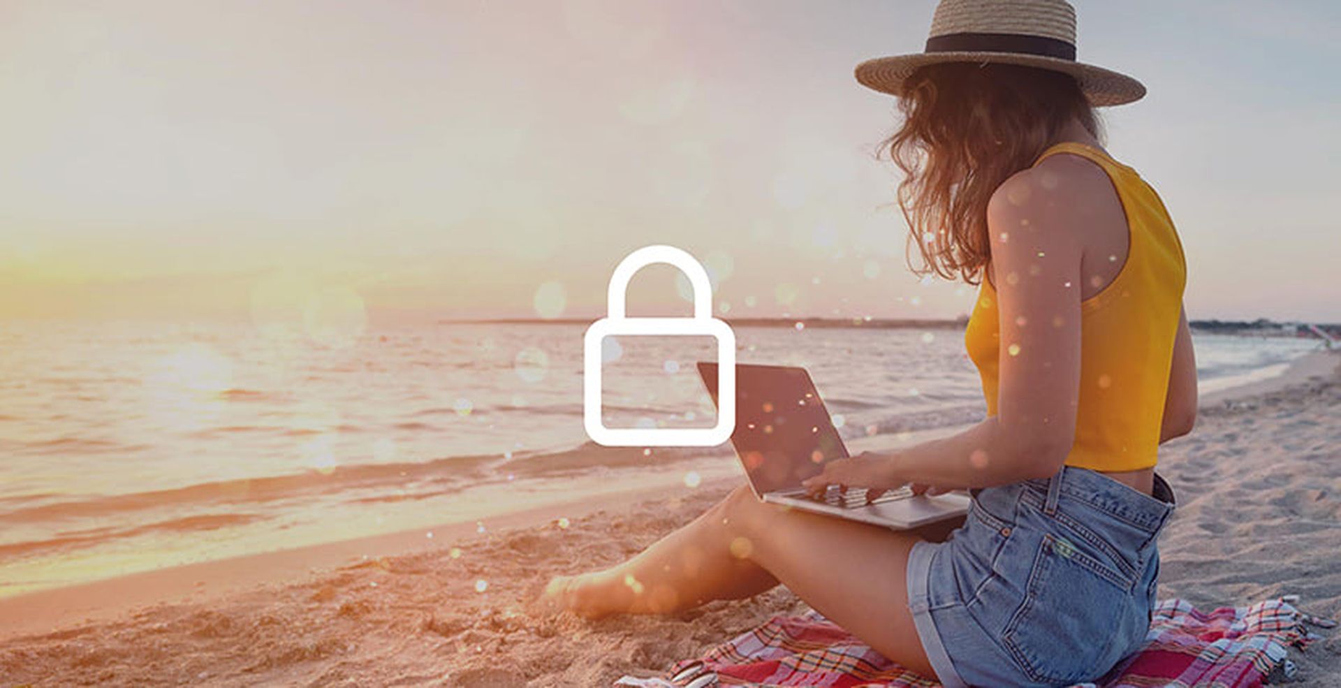Woman sitting on the beach with a laptop on her knees, wearing a hat and facing the sunset. A padlock icon overlays the image.